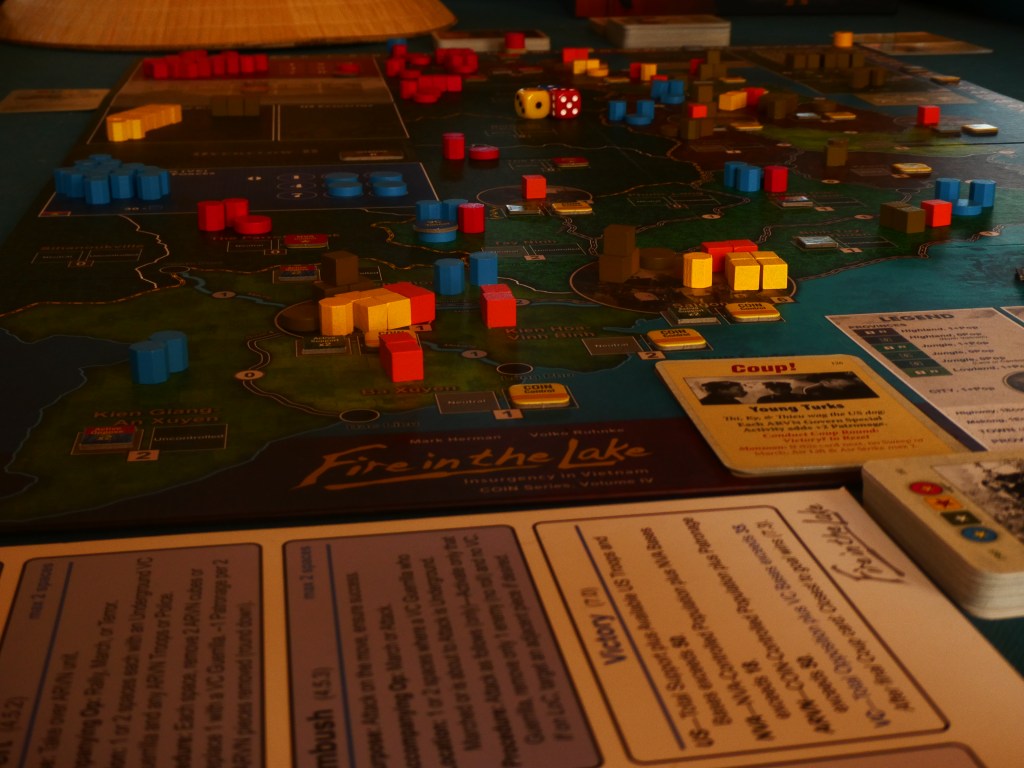 Stemningsbilde i svakt, varmt lys av brettet til Fire in the Lake.